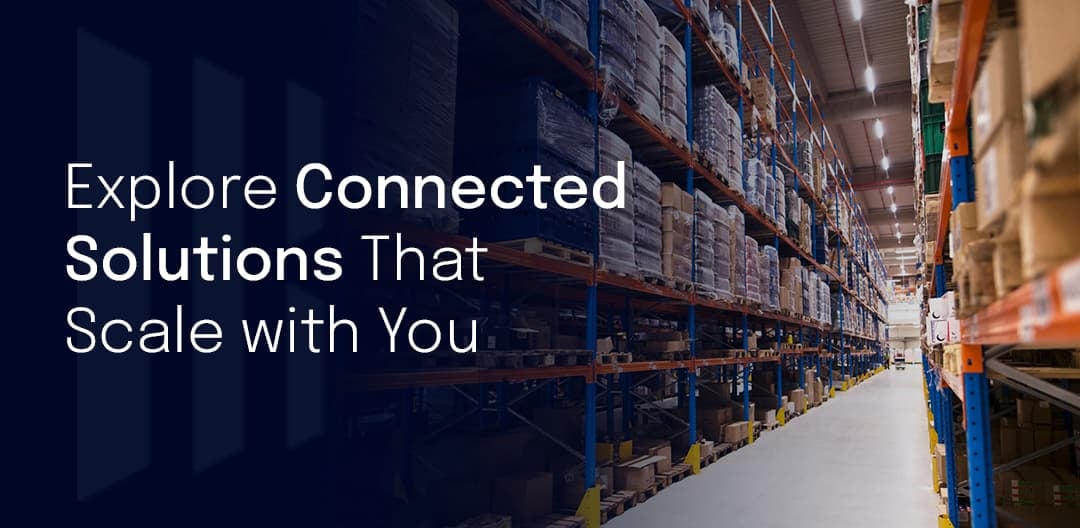 Warehouse aisle with tall shelving full of boxed inventory, overlaid with the text “Explore Connected Solutions That Scale with You.”