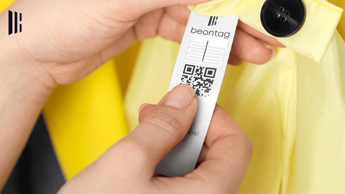 Mãos escaneando uma etiqueta RFID para roupas Fiberwave Soft da Beontag em uma peça amarela.