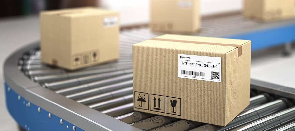 Cardboard shipping box on a conveyor belt with a Beontag RFID shipping label on the front.