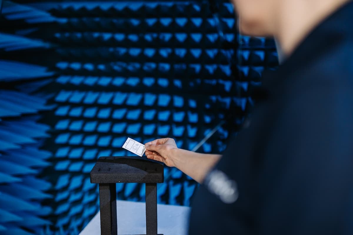 Pessoa testando uma etiqueta com antena RFID em ambiente de laboratório.