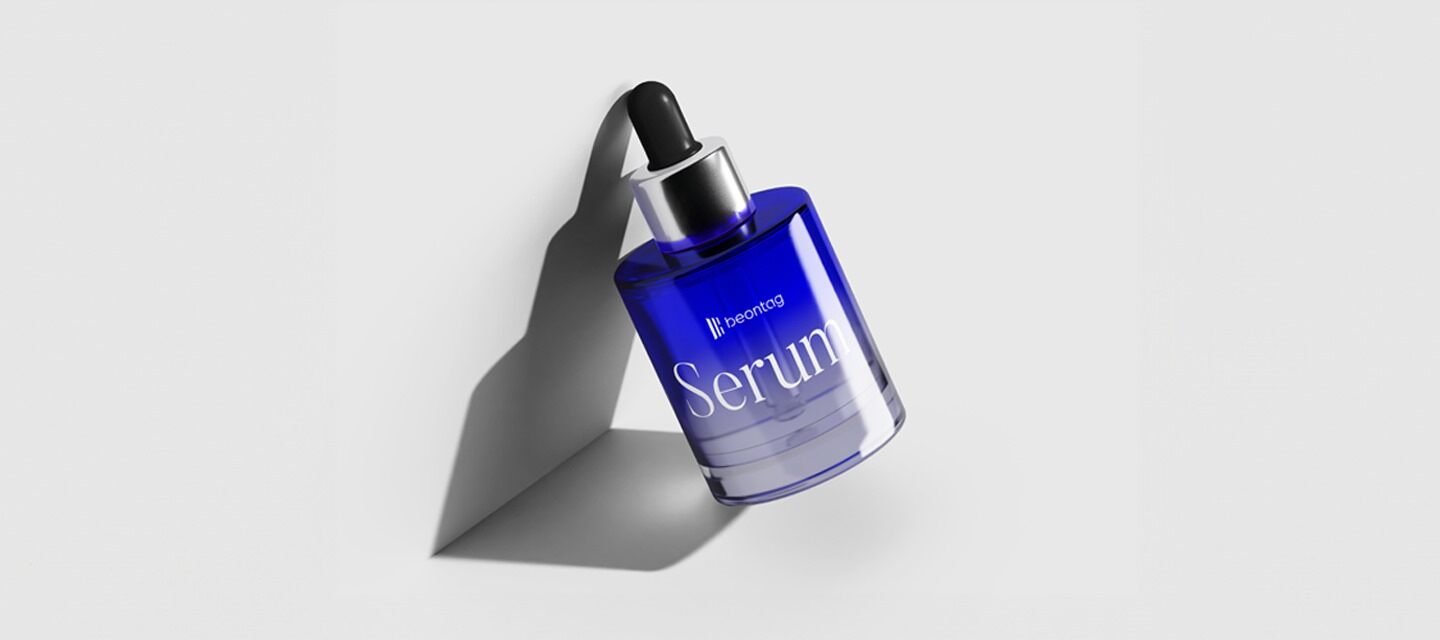 A blue glass dropper bottle labeled “Serum” with a clean, modern design, featuring a label made with thermal paper, casting a soft shadow on a white background.