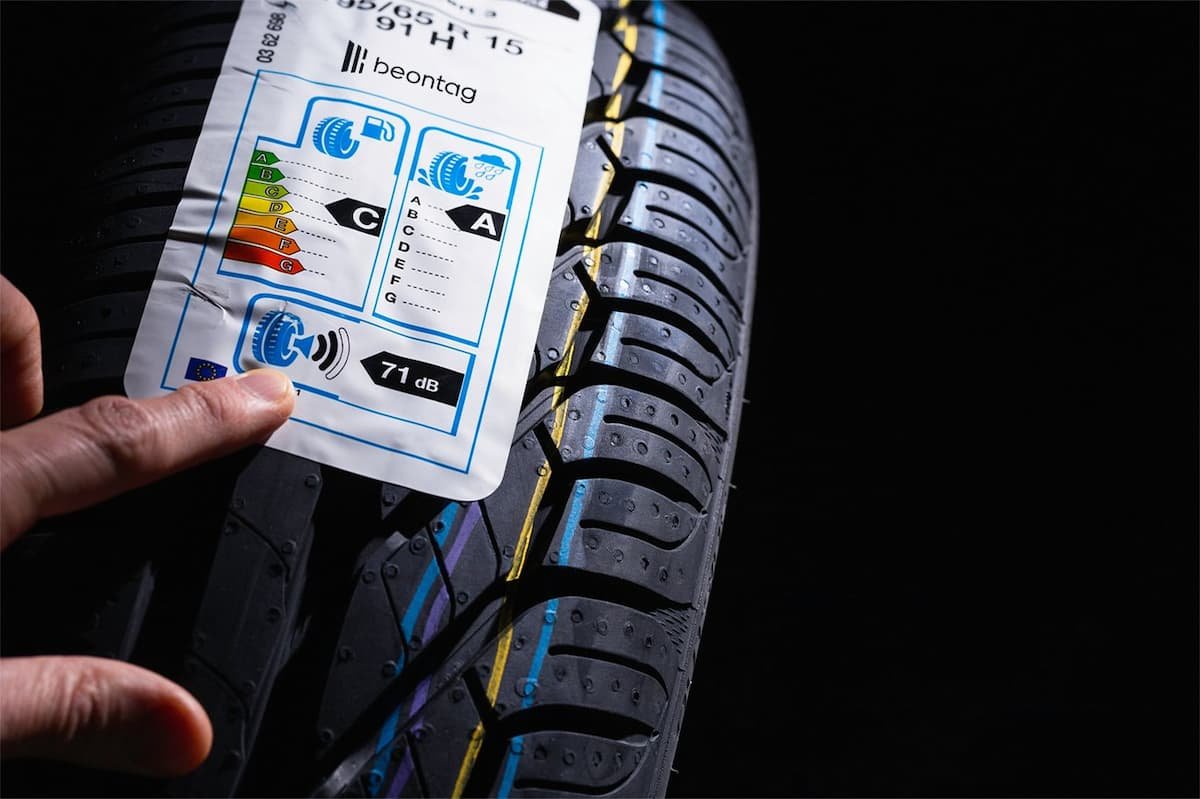 Pressure sensitive adhesive how to choose: close-up of a hand applying an EU tire label sticker onto a new car tire tread.